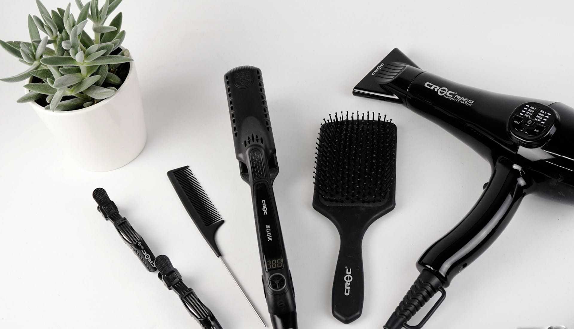 Hair styling tools and products including a hairdryer, straightener, brush, comb, and hair clips.